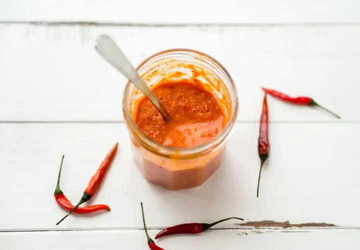 Tarro de salsa piri piri casera con chiles rojos alrededor. ¡Lista para dar sabor!