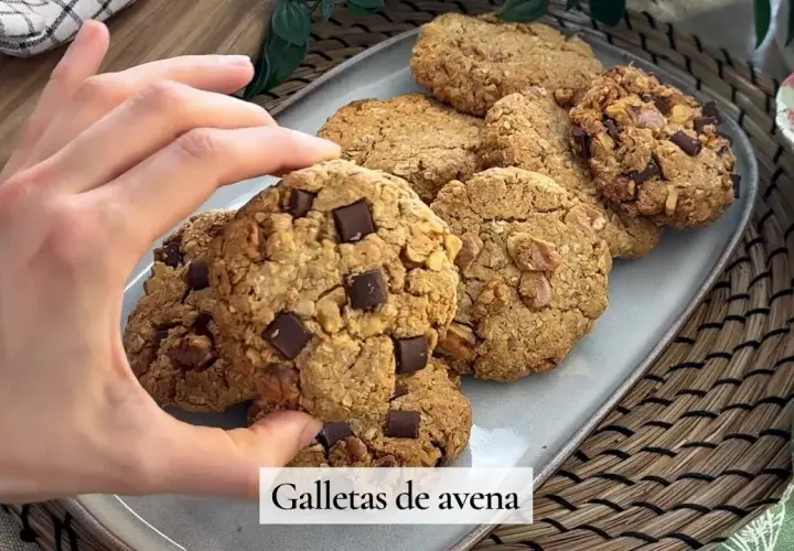 Mano tomando una galleta de avena con trozos de chocolate. Deliciosas galletas de avena caseras.