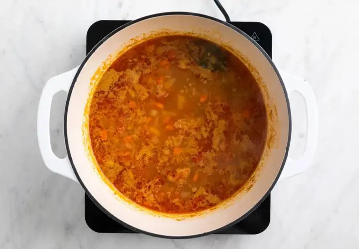 Olla con garbanzos y acelgas hirviendo, con trozos de zanahoria y especias.