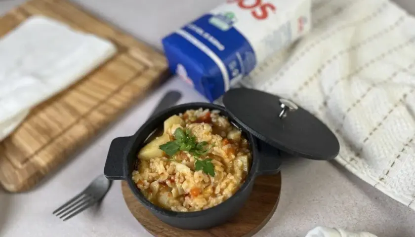 Delicioso arroz con bacalao servido en cazuela negra, listo para disfrutar.