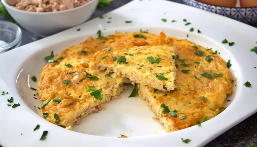 Tortilla de atún dorada y esponjosa, espolvoreada con perejil fresco. Un plato sencillo y delicioso.