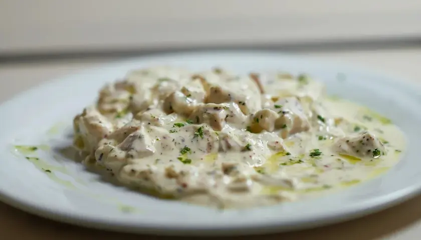 Deliciosa brandada de bacalao cremosa, espolvoreada con perejil fresco y un toque de aceite de oliva.