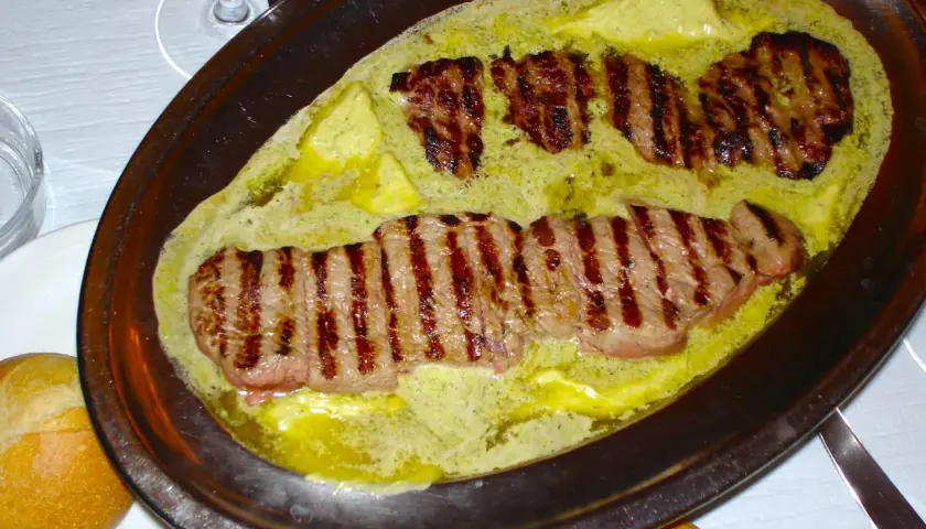 Filetes a la parrilla bañados en una cremosa salsa de mantequilla y hierbas, un plato que evoca el sabor de un café parisino.
