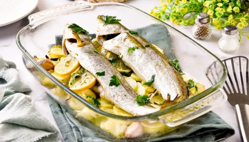 Pescadilla al horno con patatas, limón y ajo, recién salida del horno. Un plato sencillo y delicioso.