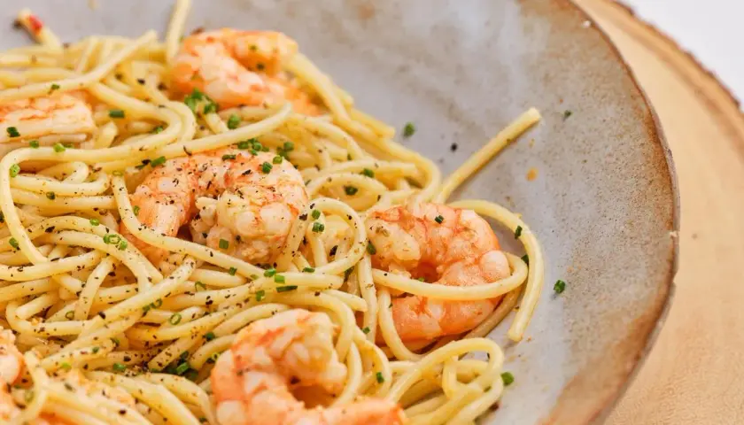 Espaguetis con gambas, un plato delicioso y fácil de preparar. La pasta se mezcla con gambas jugosas y se espolvorea con cebollino fresco.
