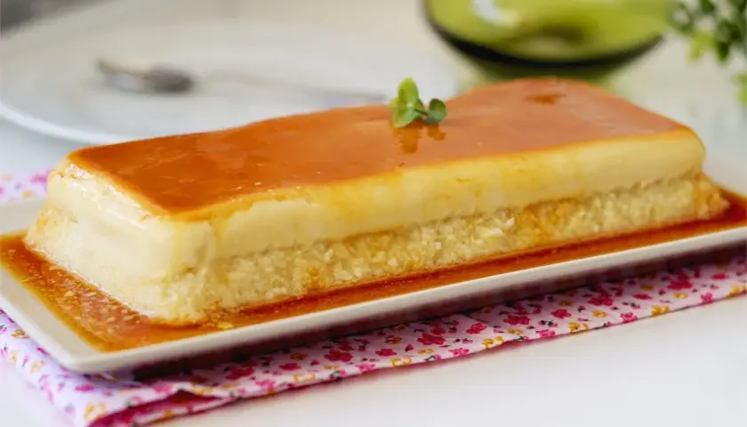 Un delicioso flan de manzana rectangular, cubierto de caramelo dorado y decorado con una ramita verde.