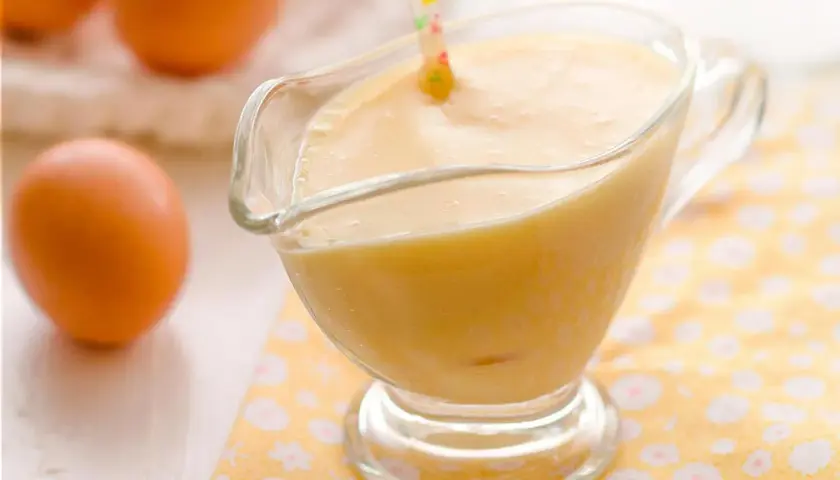 Crema pastelera suave y sedosa, lista para usar, hecha con Thermomix. Huevos frescos en el fondo.