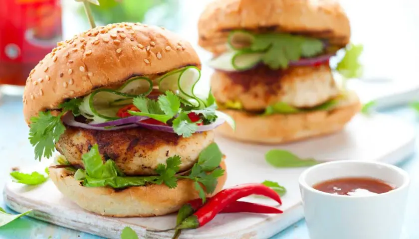 Deliciosa hamburguesa de pollo con pepino, cebolla morada y cilantro fresco. Un toque picante con chiles rojos.