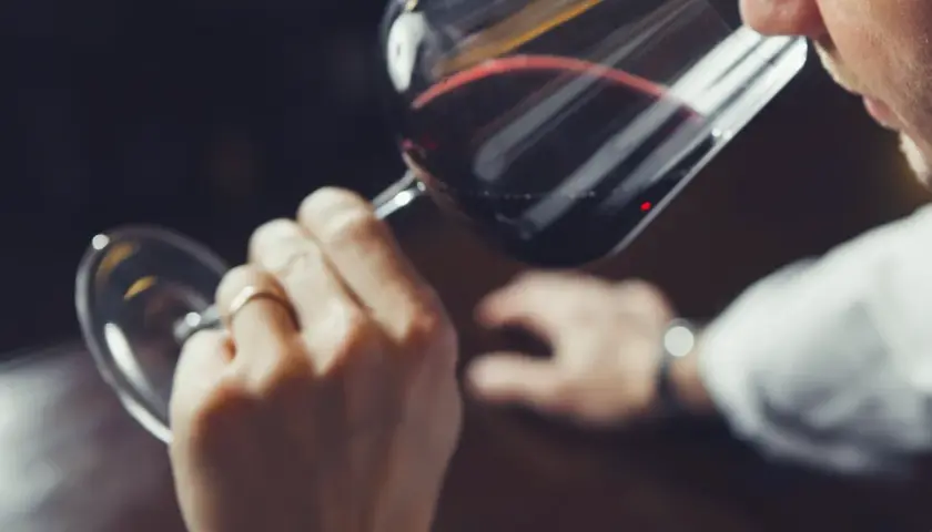 Hombre cata vino tinto, analizando su aroma. ¿Qué son los sulfitos? Se usan para conservar el vino.