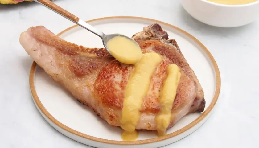 Chuleta de cerdo servida con una deliciosa salsa de piña, que realza su sabor.