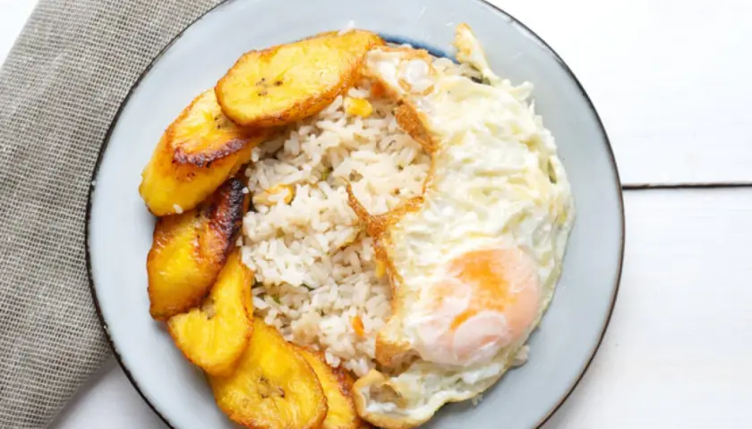 Plato de arroz a la cubana con huevo frito y plátanos maduros fritos.