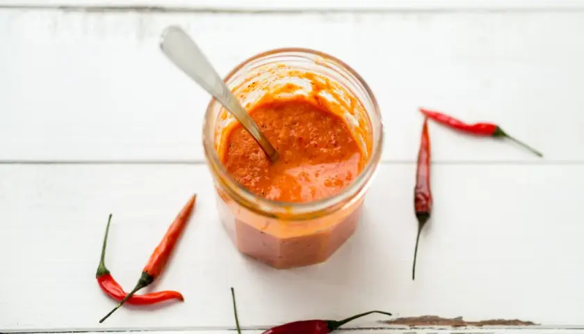 Tarro de salsa piri piri casera con chiles rojos alrededor. ¡Lista para dar sabor!