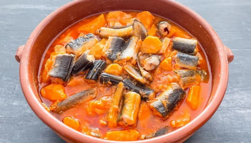 Un cuenco de barro con un sabroso all i pebre, un guiso tradicional de anguilas y patatas en salsa roja.