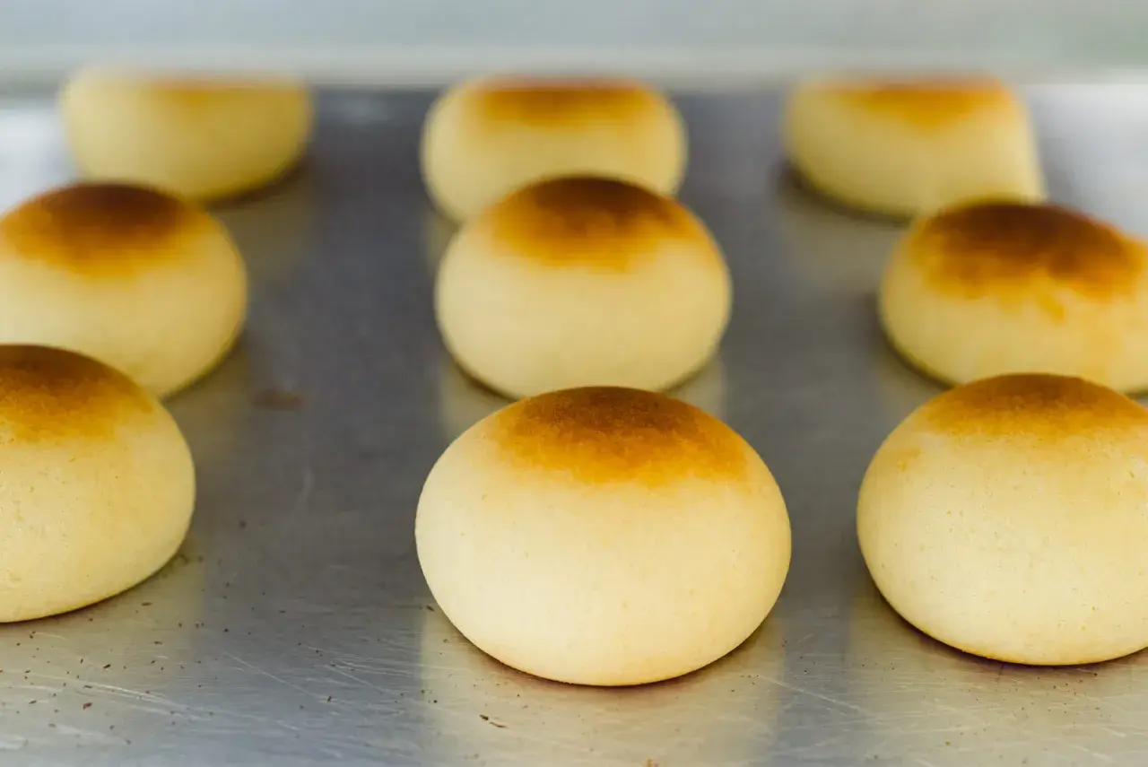 Pan de bono recién horneados, dorados y esponjosos, listos para disfrutar.
