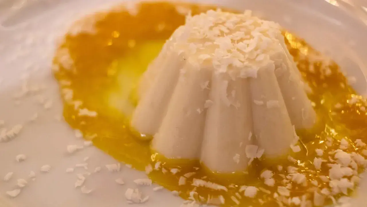 Delicioso helado de coco con salsa de mango y coco rallado, un postre tropical que te transporta al paraíso.
