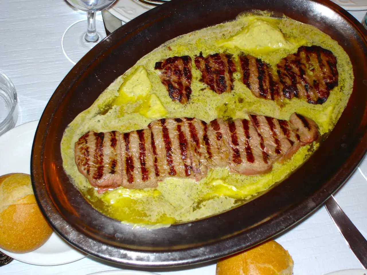 Filetes a la parrilla bañados en una cremosa salsa de mantequilla y hierbas, un plato que evoca el sabor de un café parisino.