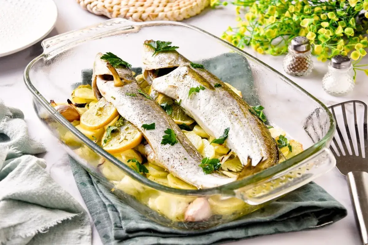 Pescadilla al horno con patatas, limón y ajo, recién salida del horno. Un plato sencillo y delicioso.
