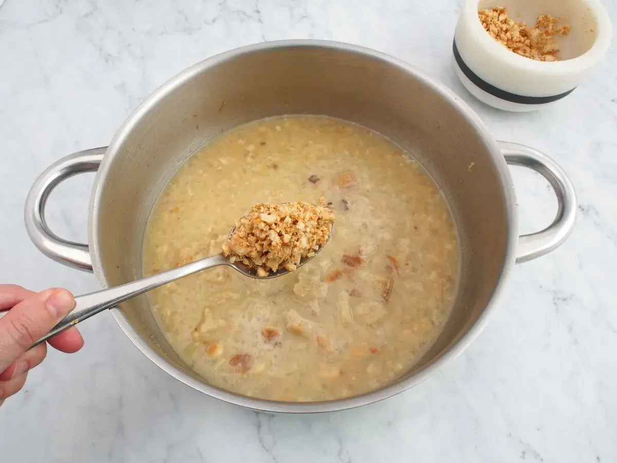 Cuchara con trozos de almendras listas para añadir a la olla, creando una deliciosa salsa de almendras.