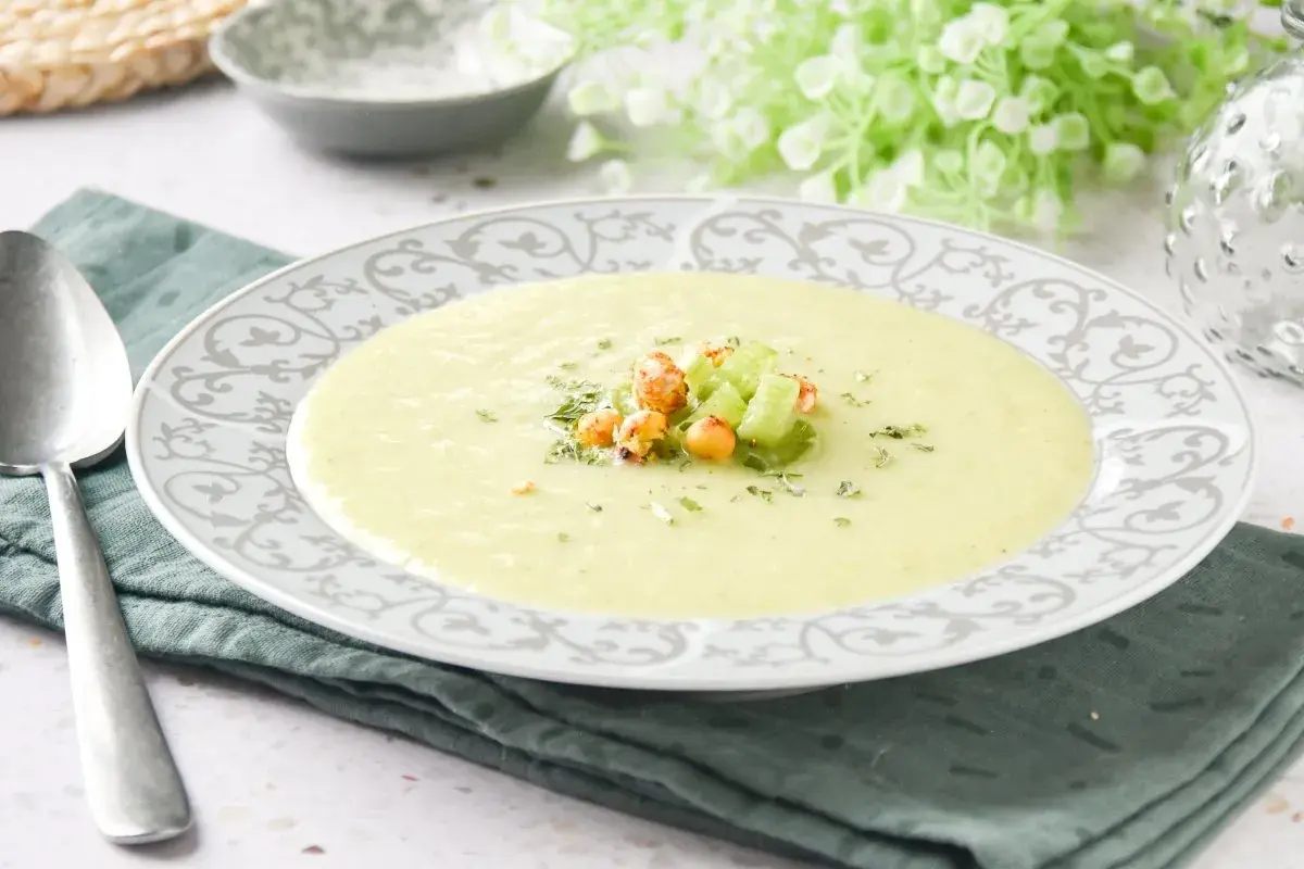 Crema de apio suave y reconfortante, decorada con trocitos de apio fresco y garbanzos crujientes.