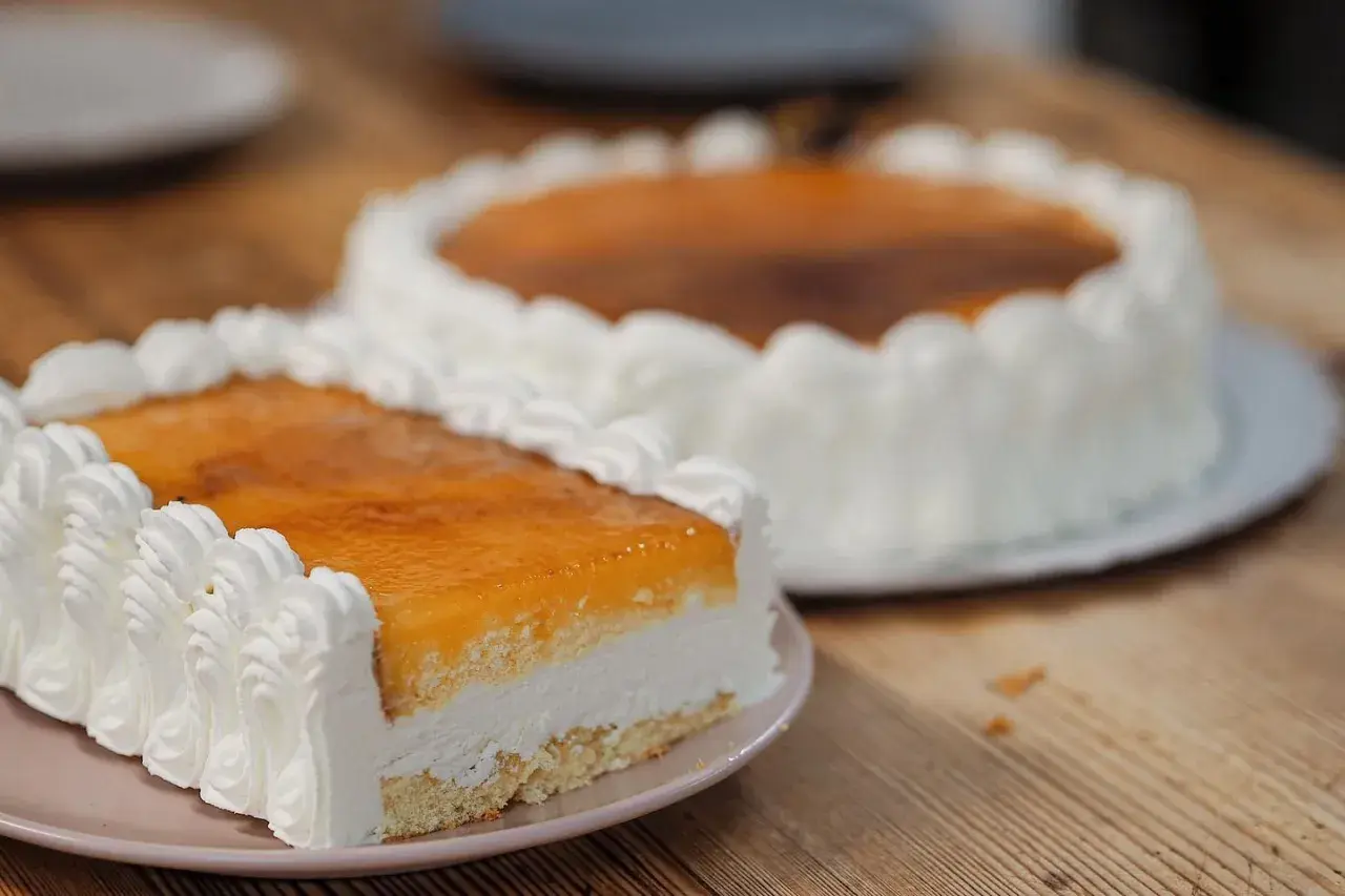 Dos deliciosas tartas San Marcos, una rectangular y otra redonda, cubiertas de crema y glaseado dorado, listas para disfrutar.