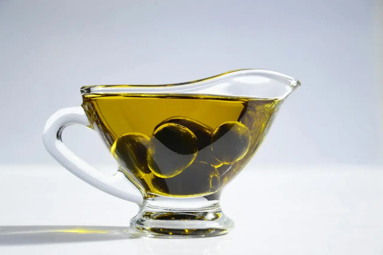 Aceite de oliva para el pelo en una salsera de cristal con aceitunas. Un ingrediente natural para un cabello radiante.