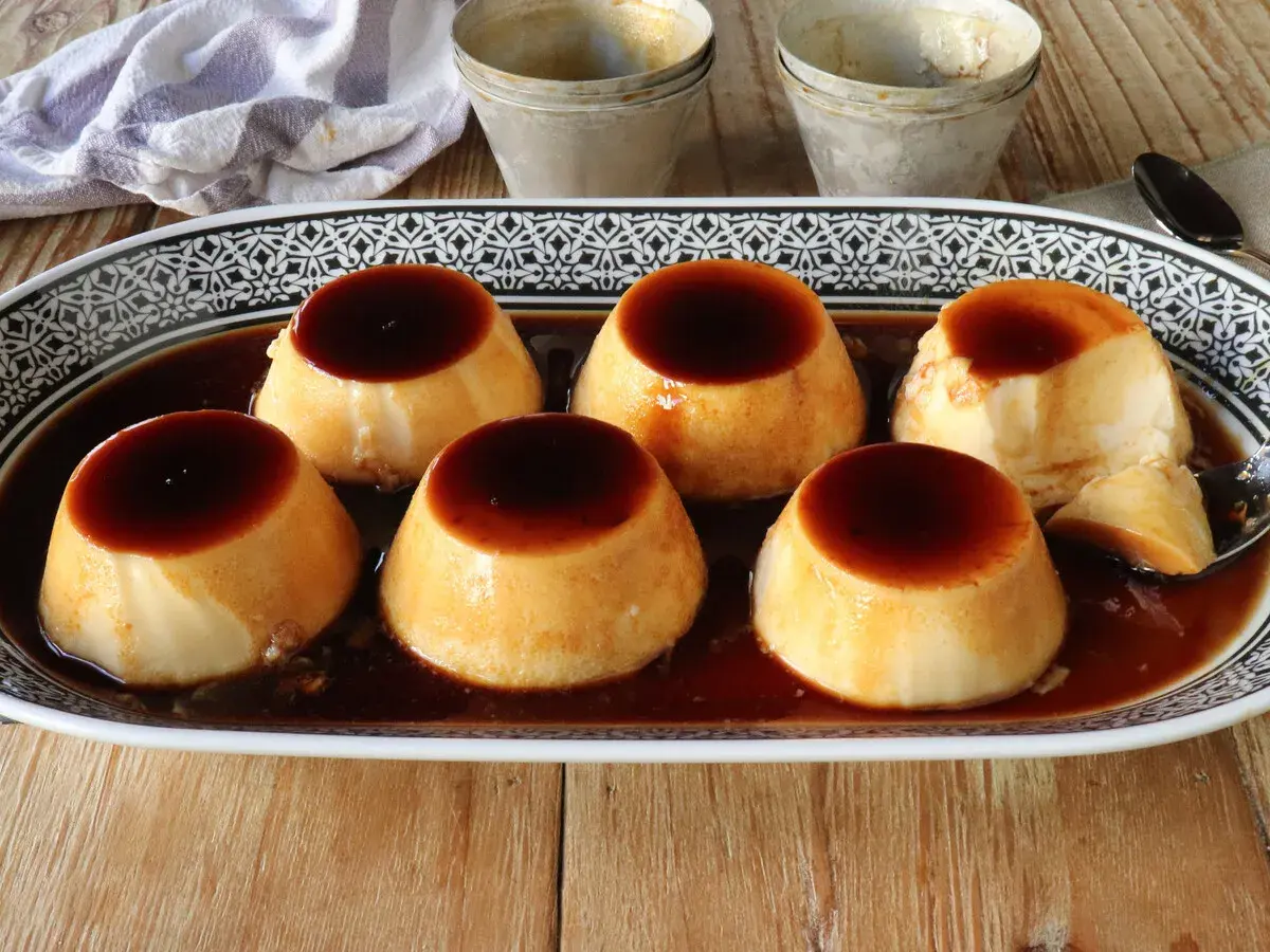 Seis deliciosos flanes de leche condensada, bañados en caramelo líquido, servidos en una bandeja decorada.