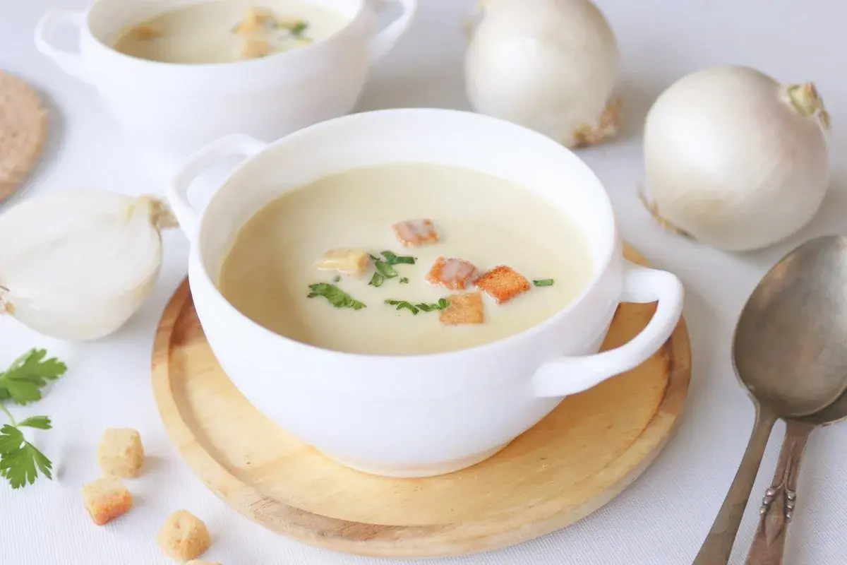 Crema reconfortante de cebolla, adornada con picatostes crujientes y perejil fresco.