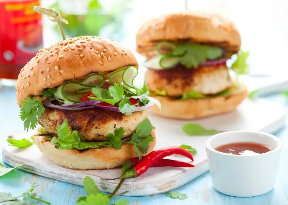 Deliciosa hamburguesa de pollo con pepino, cebolla morada y cilantro fresco. Un toque picante con chiles rojos.