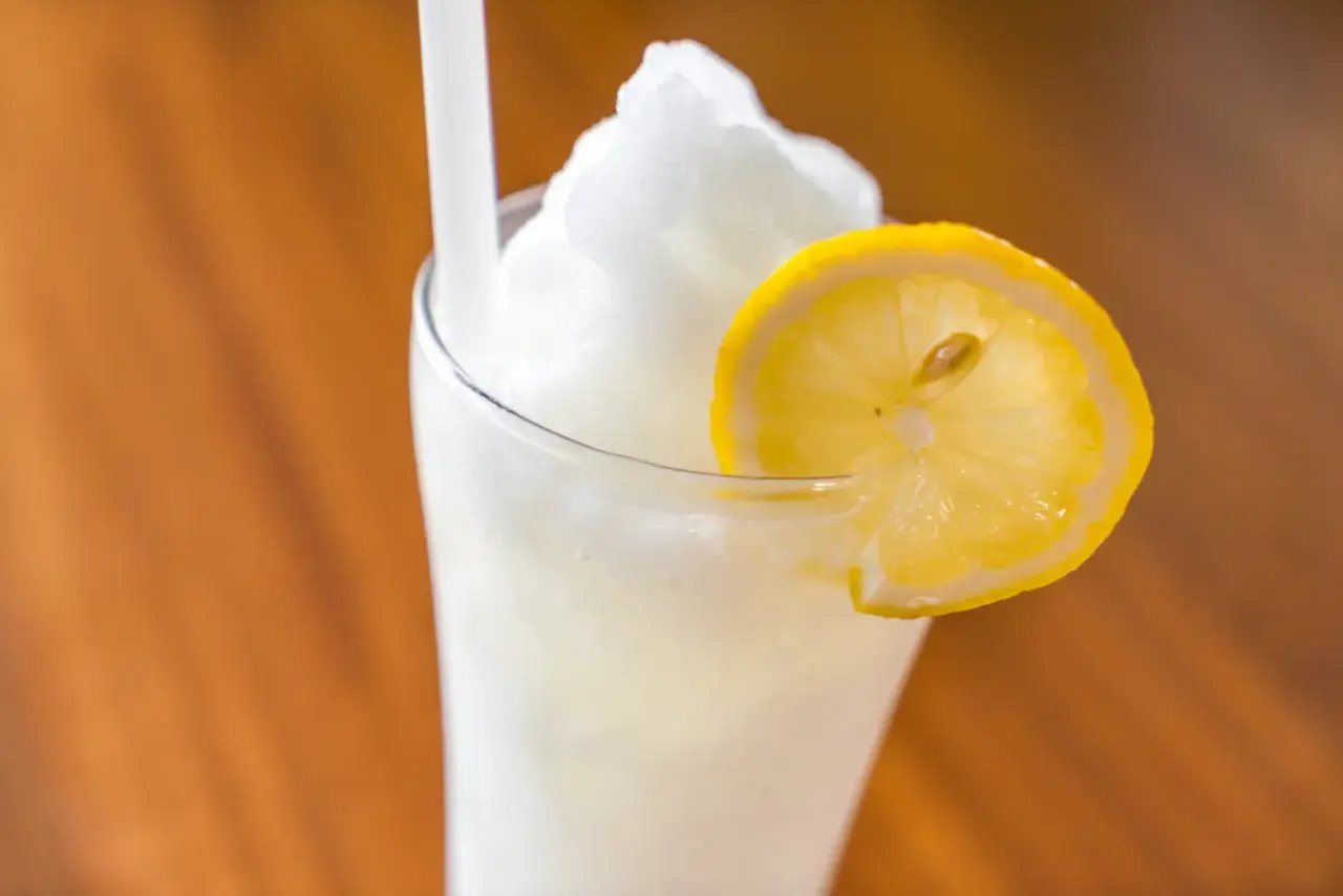 Un refrescante granizado de limón, coronado con una rodaja de limón fresco, listo para disfrutar en un día caluroso.