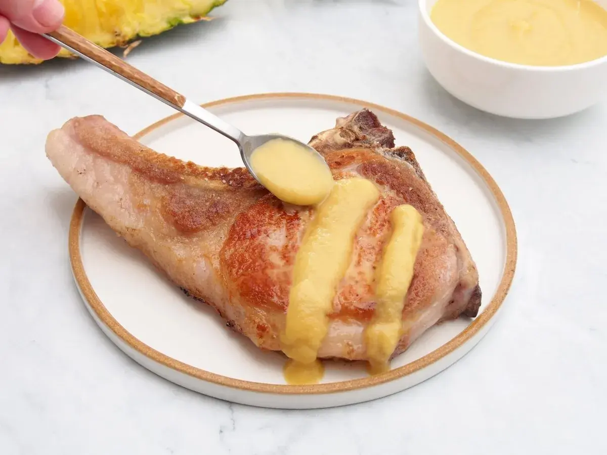 Chuleta de cerdo servida con una deliciosa salsa de piña, que realza su sabor.