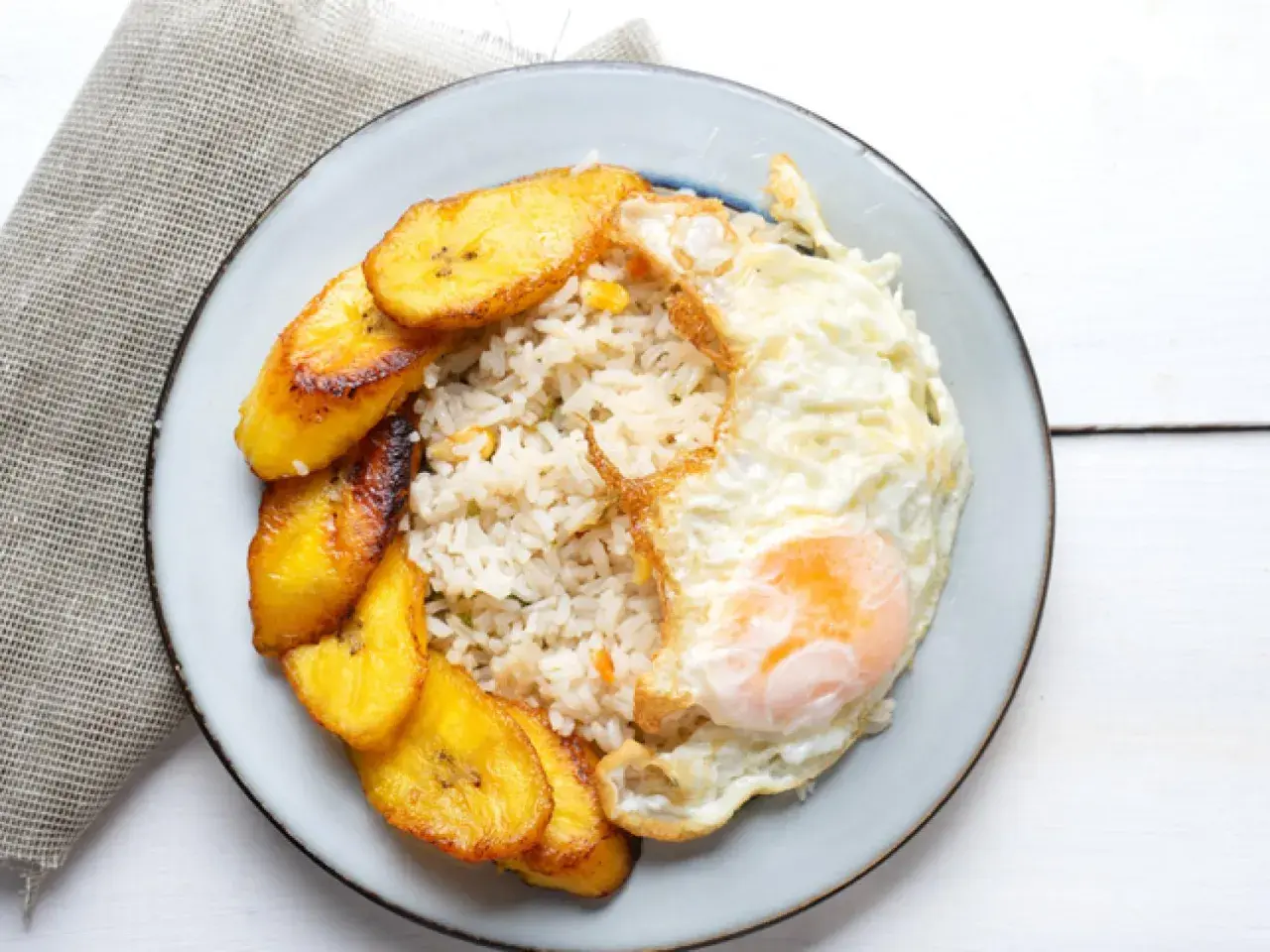 Plato de arroz a la cubana con huevo frito y plátanos maduros fritos.
