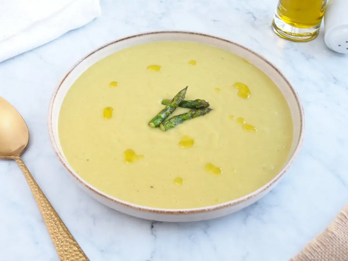 Deliciosa crema de esparragos trigueros, servida en un cuenco con un chorrito de aceite de oliva y espárragos frescos.