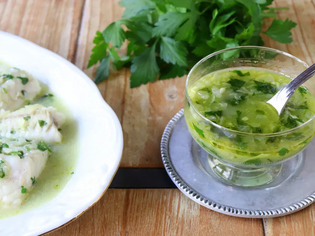 Pescado blanco bañado en una deliciosa salsa verde, con un cuenco de la misma salsa al lado.