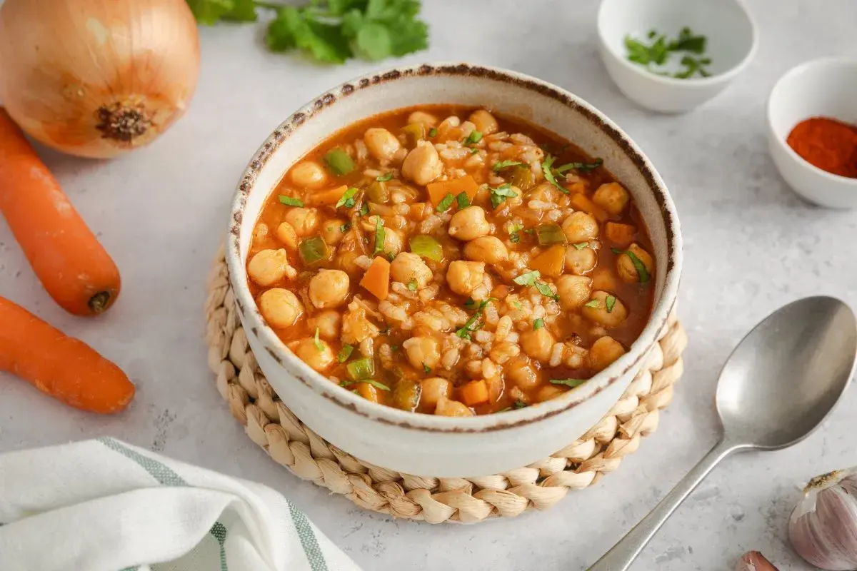 Un reconfortante plato de garbanzos con arroz, zanahorias y pimientos verdes, adornado con perejil fresco.