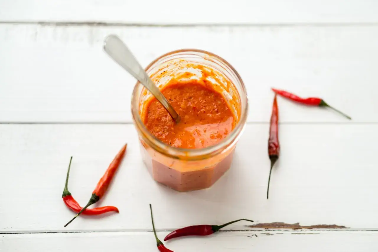 Tarro de salsa piri piri casera con chiles rojos alrededor. ¡Lista para dar sabor!