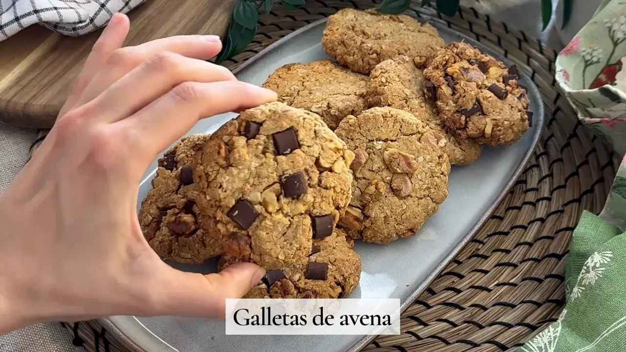 Mano tomando una galleta de avena con trozos de chocolate. Deliciosas galletas de avena caseras.