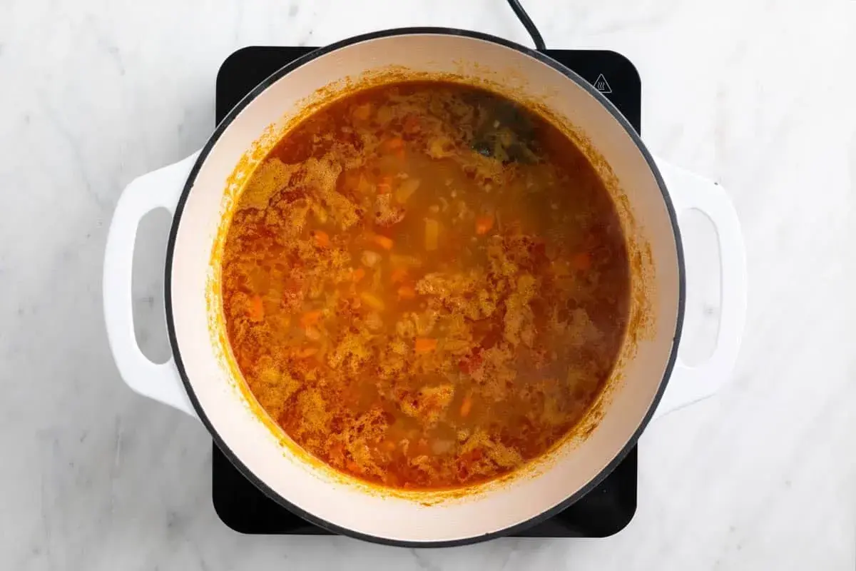 Olla con garbanzos y acelgas hirviendo, con trozos de zanahoria y especias.