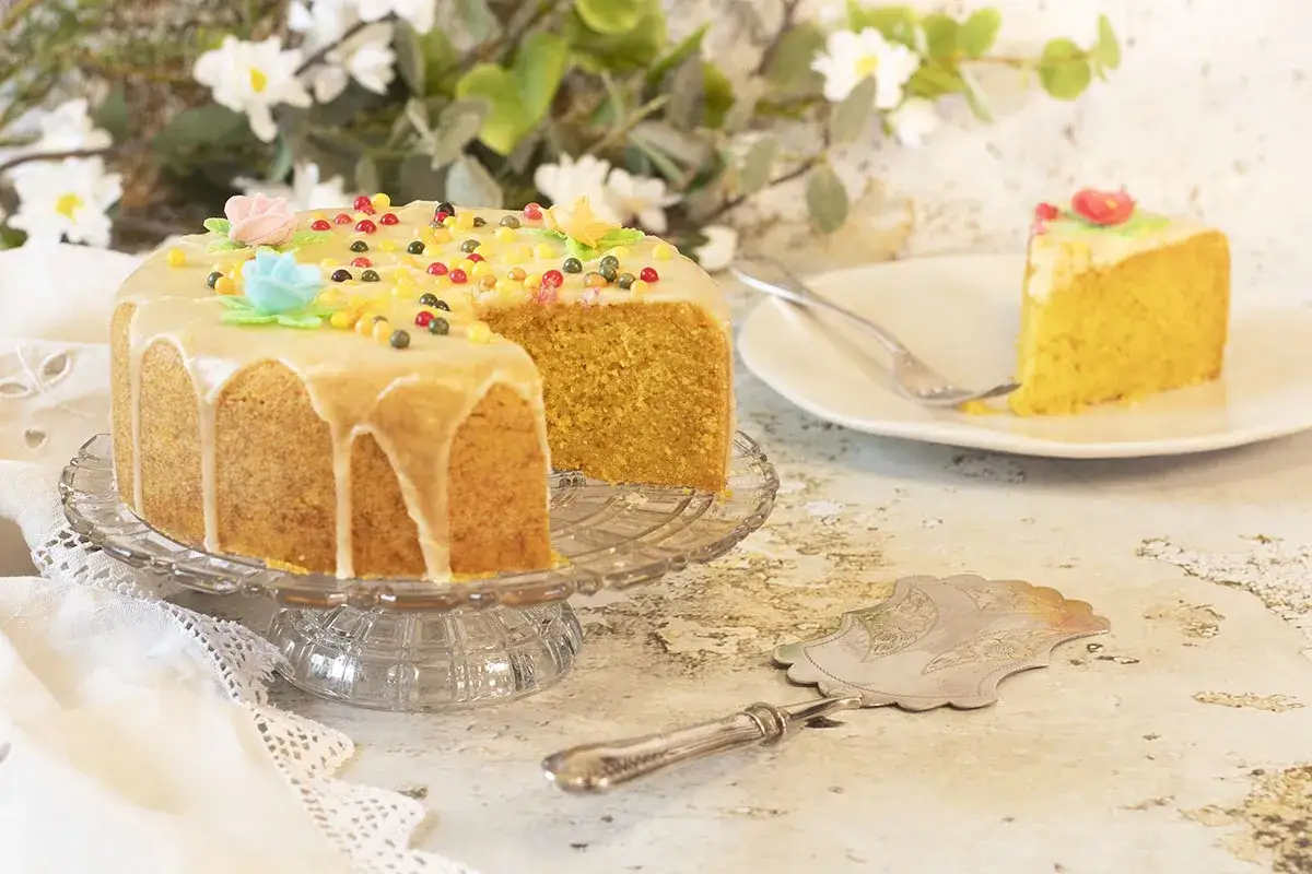 Deliciosa tarta de naranja con glaseado y decoraciones de colores. Un trozo ya servido en un plato.