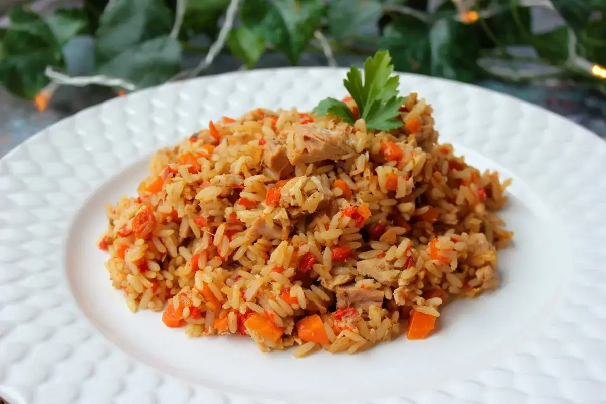 Delicioso arroz con atún, zanahoria y pimientos rojos, adornado con perejil fresco. Un plato sencillo y sabroso.