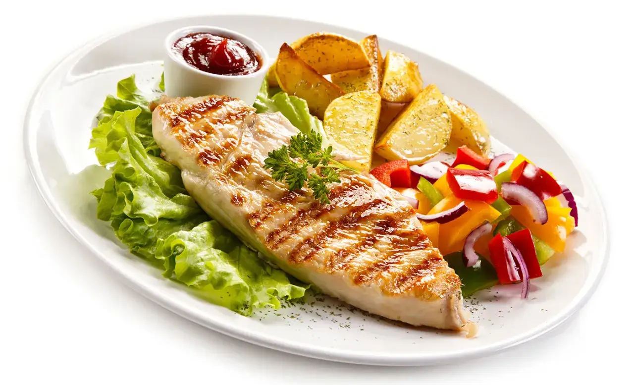Delicioso solomillo de pollo a la parrilla con patatas asadas, ensalada de pimientos y cebolla, y una guarnición de lechuga fresca.