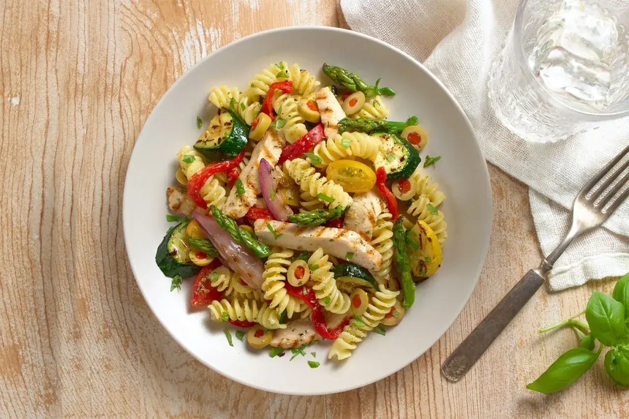Deliciosa ensalada de pasta con pollo a la parrilla, calabac&iacute;n, pimientos rojos, esp&aacute;rragos y aceitunas.