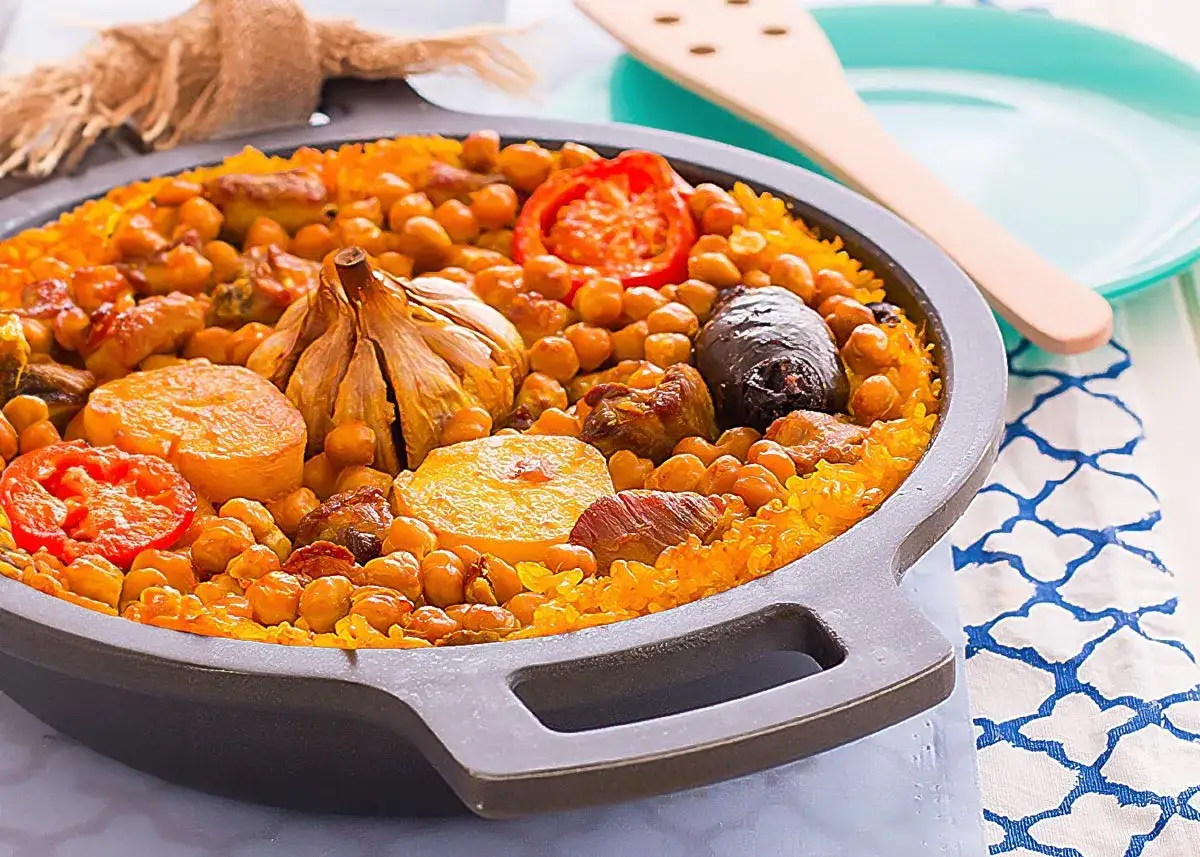 Delicioso arroz al horno con garbanzos, carne, tomate y una cabeza de ajo asada.