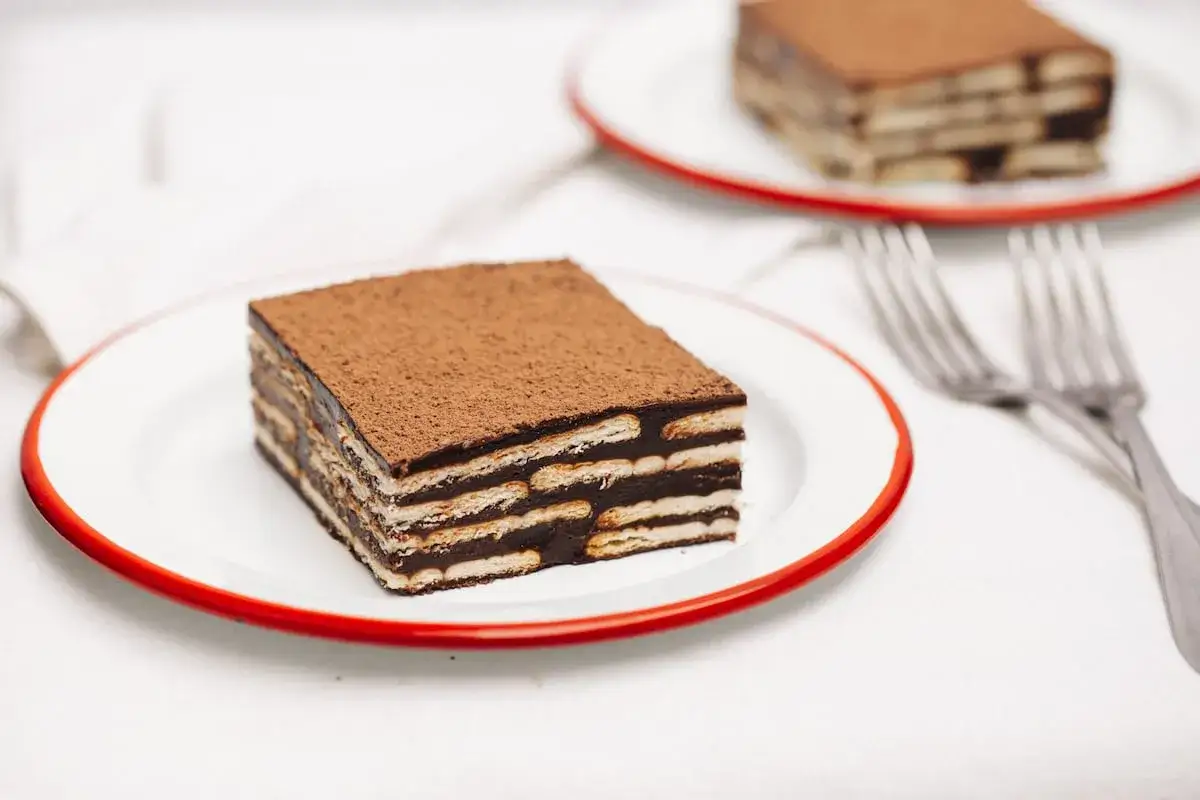 Deliciosa marquesa de chocolate, capas de galleta y crema de cacao, espolvoreada con cacao en polvo.