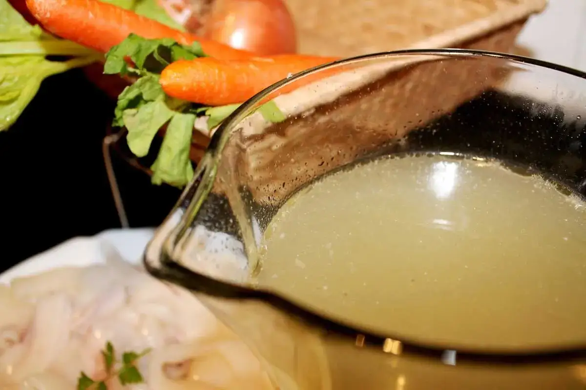 Caldo de pescado casero listo para usar. Zanahorias, cebolla y apio en el fondo.