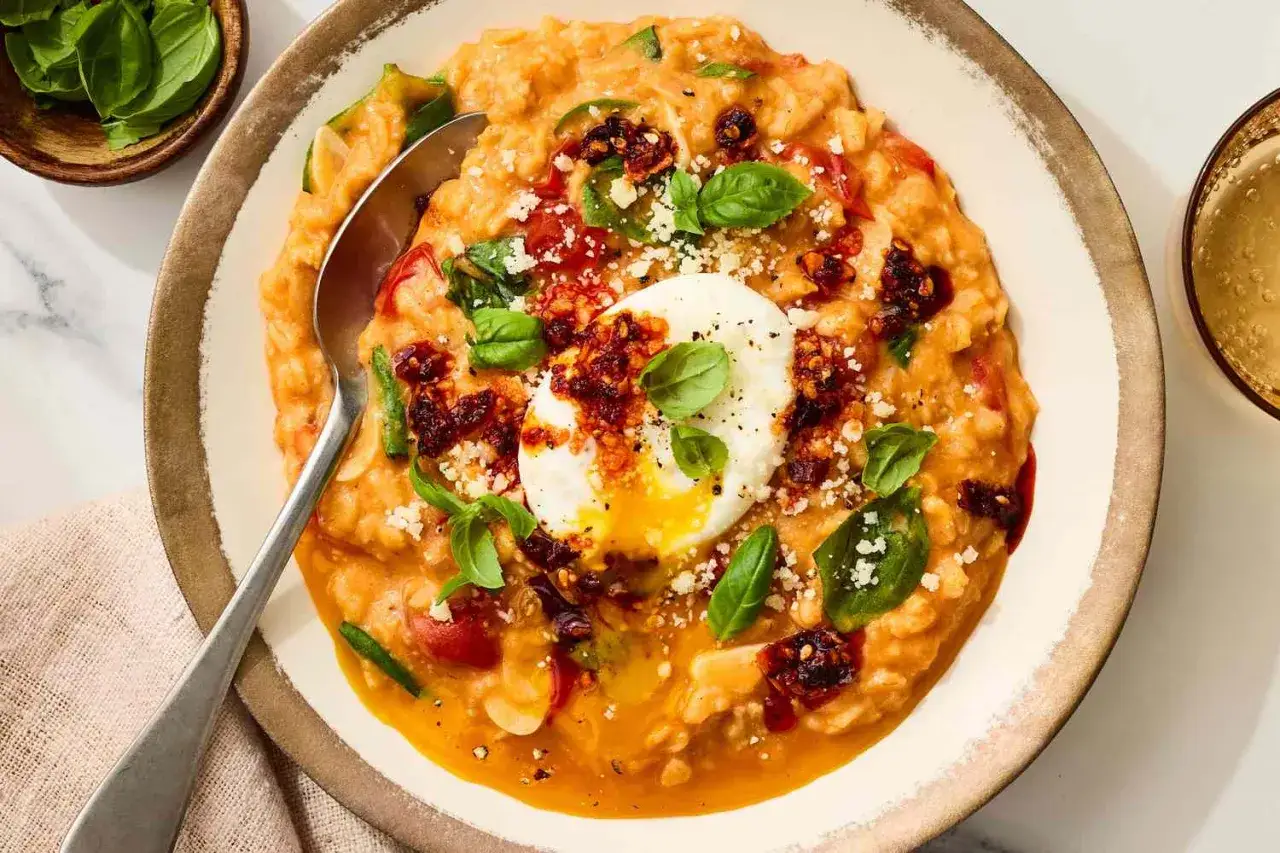 Un cremoso porridge de avena con huevo escalfado, tomates secos, albahaca fresca y queso rallado.