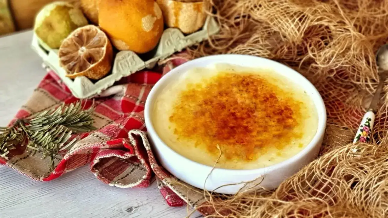 Crema catalana Thermomix con costra dorada, servida en cuenco blanco, junto a frutas y romero.