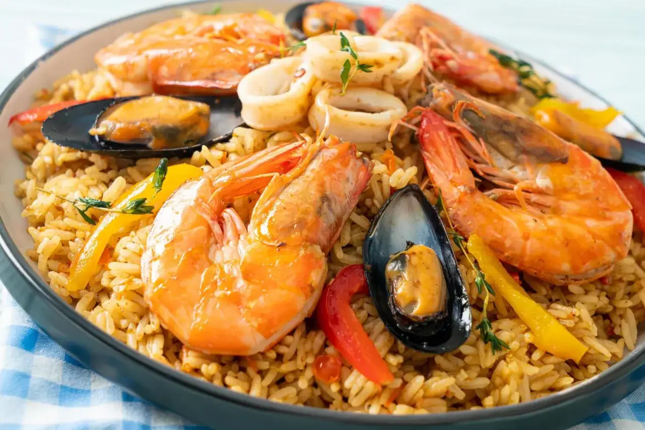 Delicioso arroz con marisco, coronado con gambas, mejillones y anillas de calamar, adornado con pimientos de colores.