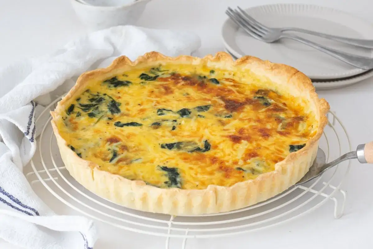 Un delicioso quiche de espinacas recién horneado, con masa dorada y relleno cremoso, listo para ser servido.