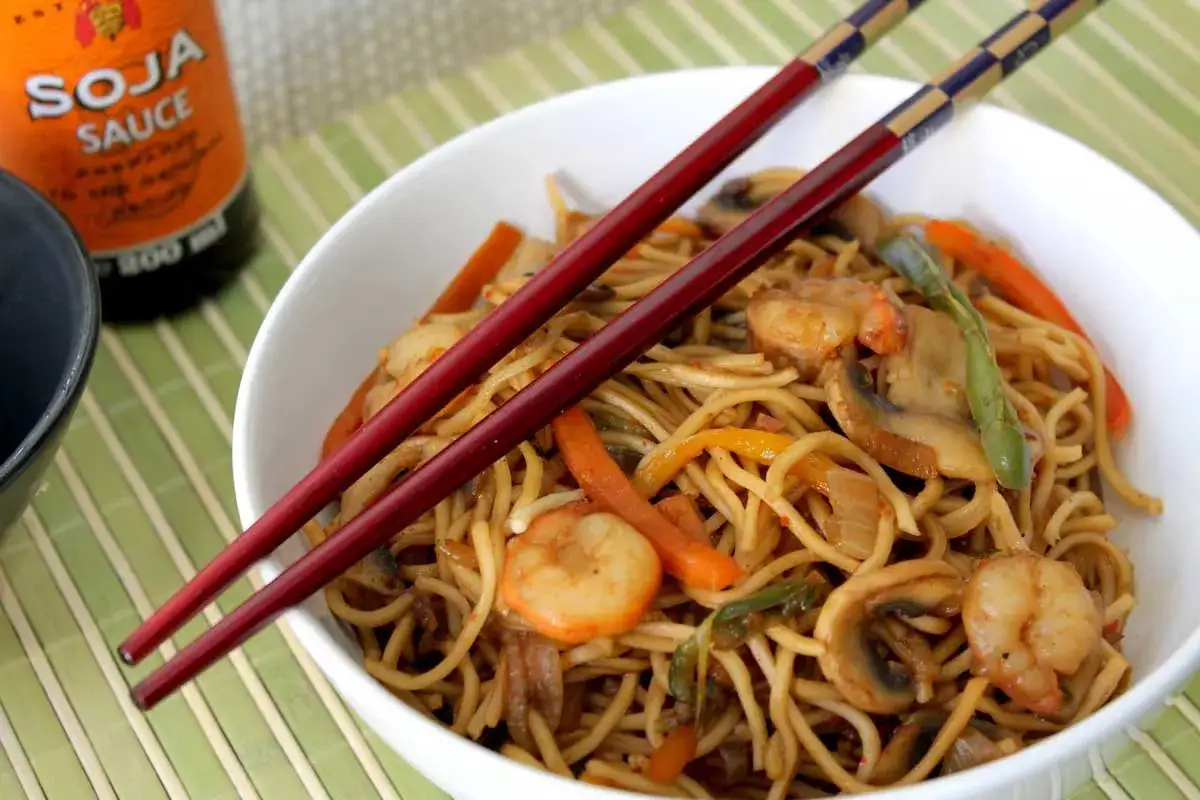 Deliciosos fideos de arroz con gambas, champi&ntilde;ones y verduras, listos para disfrutar con palillos.