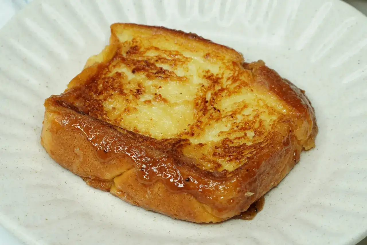 Torrijas doradas y jugosas hechas con pan brioche, servidas en un plato blanco.